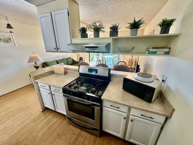 kitchen with light wood-type flooring, a textured ceiling, extractor fan, stainless steel gas stove, and white cabinetry