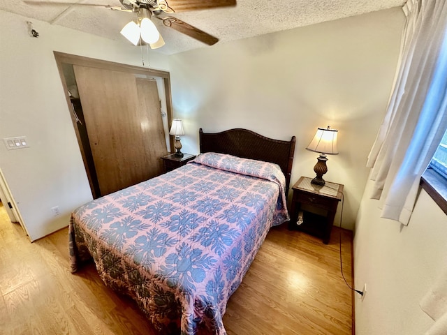 bedroom with a textured ceiling, light wood-type flooring, and ceiling fan