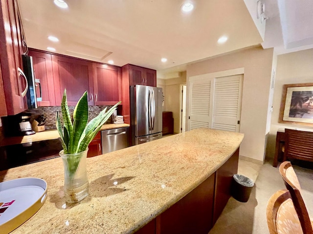 kitchen with light stone counters, stainless steel appliances, and backsplash