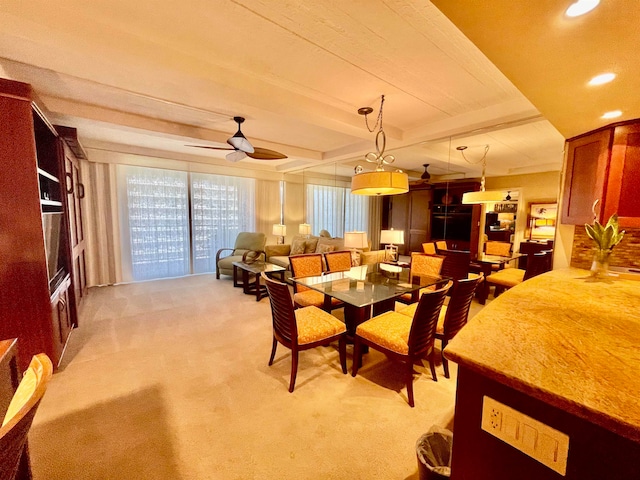 dining area featuring light carpet, beamed ceiling, and ceiling fan