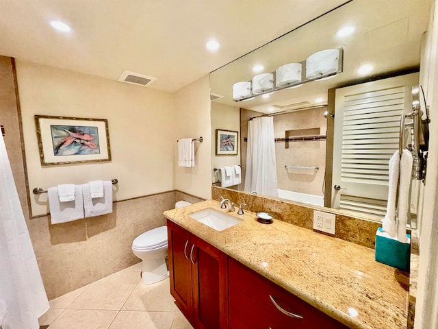 bathroom with tile patterned floors, vanity, tile walls, and toilet