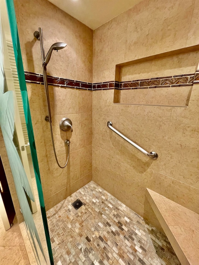 bathroom with a tile shower and tile patterned flooring