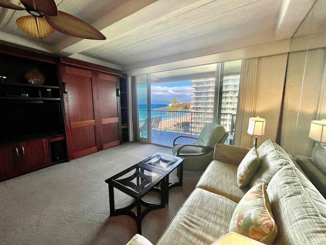 living room featuring ceiling fan, a water view, and carpet floors