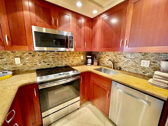 kitchen with light tile patterned flooring, appliances with stainless steel finishes, decorative backsplash, and light stone countertops