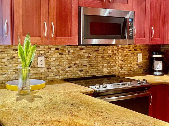 kitchen with appliances with stainless steel finishes, light stone counters, and decorative backsplash