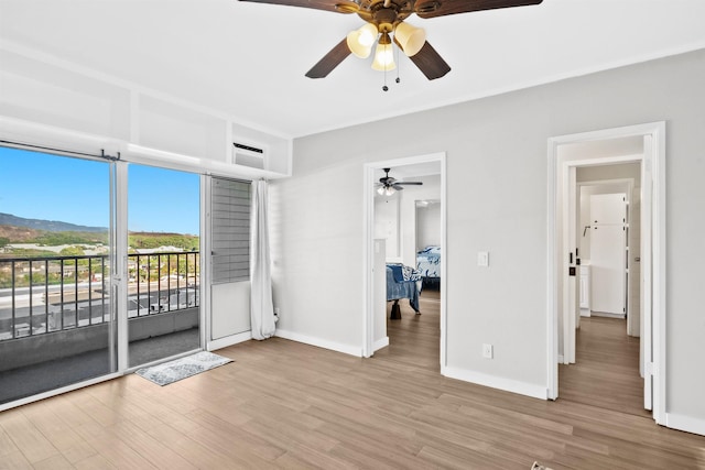 spare room featuring a mountain view, light hardwood / wood-style flooring, and ceiling fan