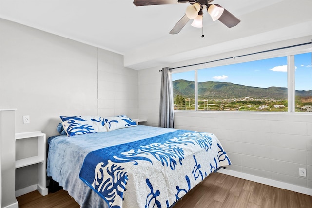 bedroom featuring multiple windows, a mountain view, ceiling fan, and dark wood-type flooring