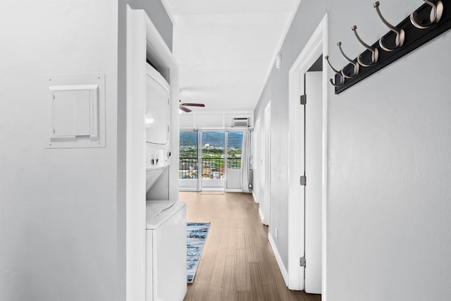 corridor with hardwood / wood-style flooring and stacked washer / dryer