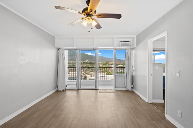 spare room with a wall mounted AC, ceiling fan, and hardwood / wood-style flooring