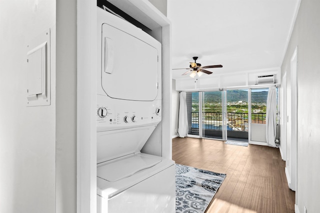 laundry room with stacked washer / drying machine, ceiling fan, and dark hardwood / wood-style floors