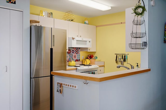 kitchen with sink, stainless steel fridge, white cabinets, and range