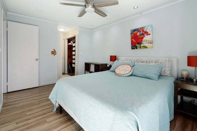 bedroom featuring hardwood / wood-style flooring, ornamental molding, a spacious closet, ceiling fan, and a closet