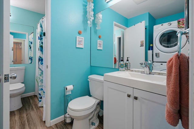 bathroom featuring vanity, hardwood / wood-style flooring, toilet, and stacked washing maching and dryer