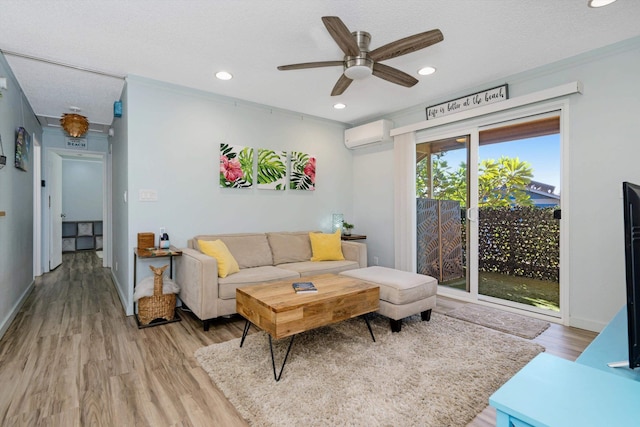 living room featuring light hardwood / wood-style flooring, a wall unit AC, and ceiling fan