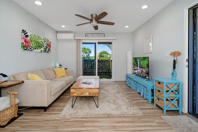 living room featuring ceiling fan, light wood-type flooring, a textured ceiling, and an AC wall unit