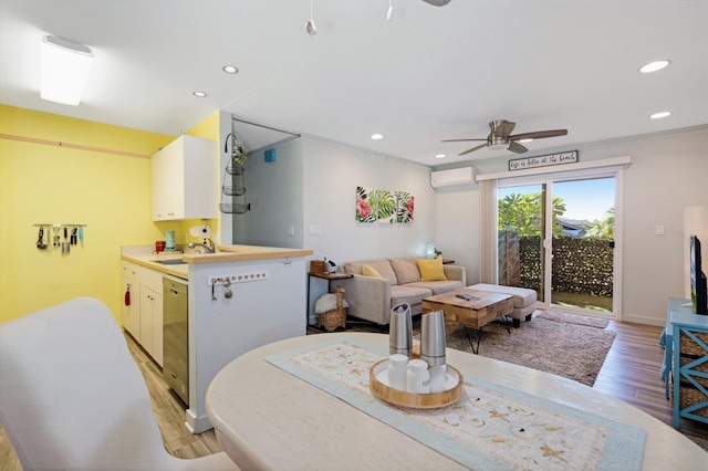 dining area featuring ceiling fan, a wall mounted AC, sink, and light wood-type flooring