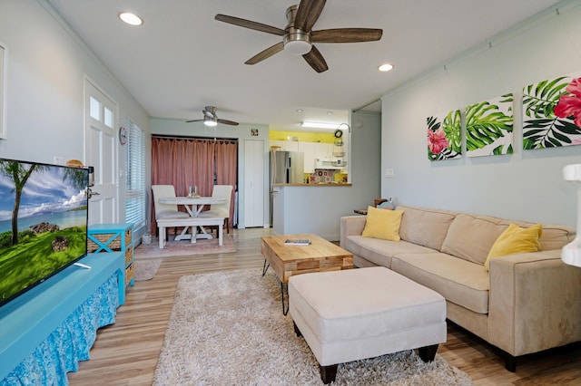 living room featuring hardwood / wood-style flooring, ceiling fan, and ornamental molding