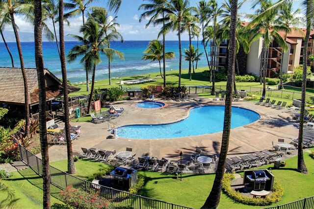 view of swimming pool with a hot tub, a lawn, a water view, and a patio