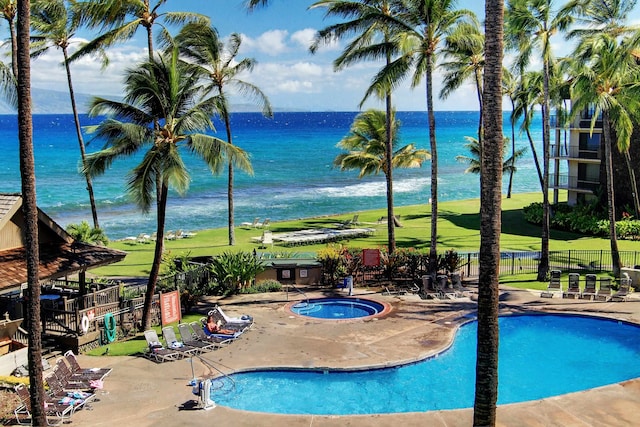 view of pool featuring a community hot tub, a water view, and a patio