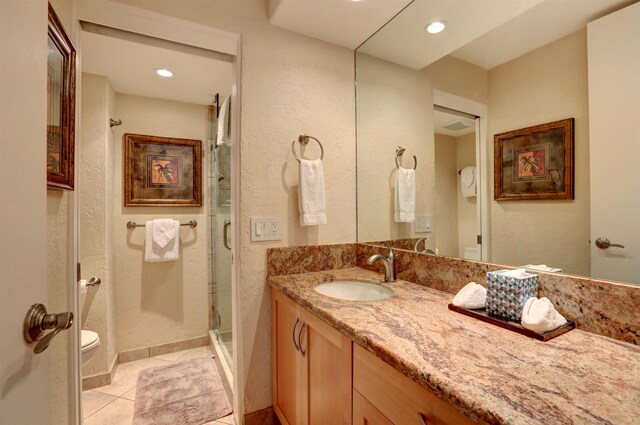 bathroom featuring toilet, vanity, walk in shower, and tile patterned flooring