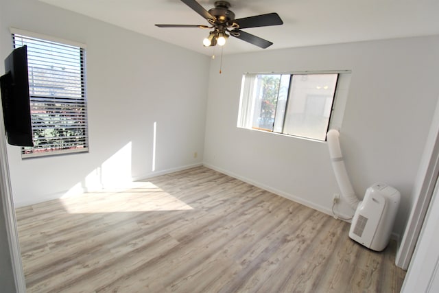 spare room featuring light hardwood / wood-style floors, a healthy amount of sunlight, and ceiling fan