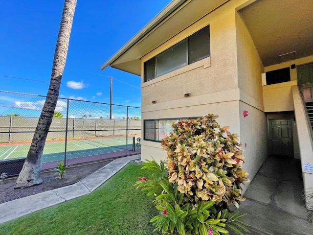 view of home's exterior with tennis court