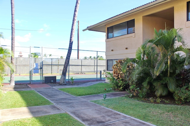 view of home's community featuring a yard and tennis court