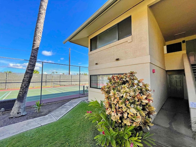 view of home's exterior featuring tennis court