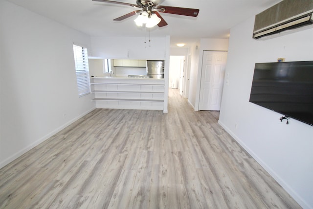 unfurnished living room featuring a wall unit AC, sink, light wood-type flooring, and ceiling fan