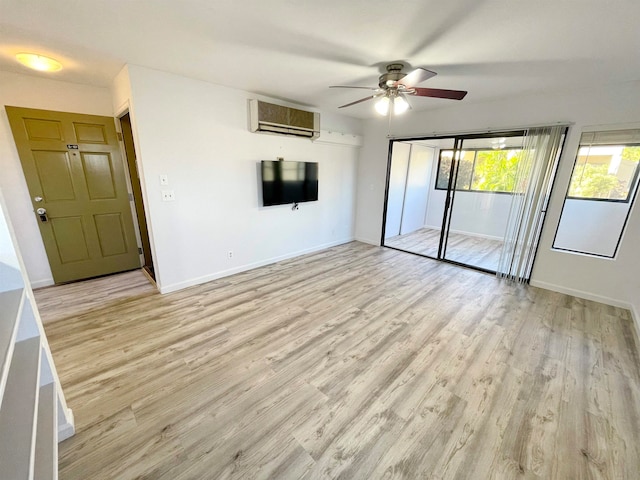 empty room with light hardwood / wood-style flooring, a wall unit AC, and ceiling fan