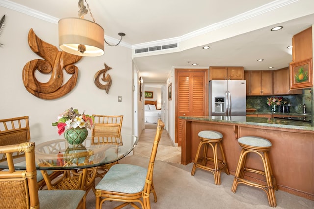 kitchen featuring stainless steel refrigerator with ice dispenser, tasteful backsplash, visible vents, ornamental molding, and brown cabinetry