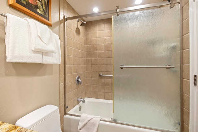 bathroom with toilet and bath / shower combo with glass door