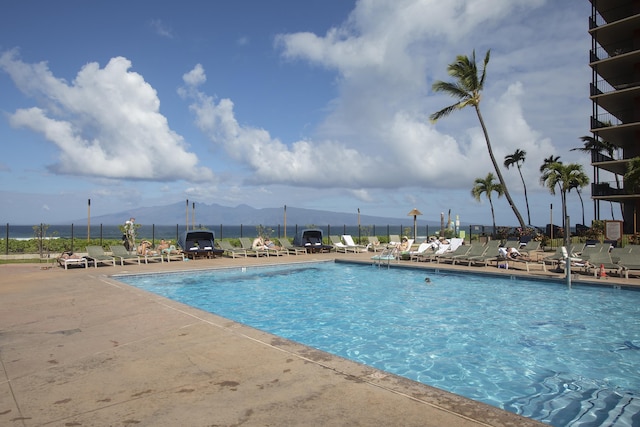 community pool with a patio area, a mountain view, and fence