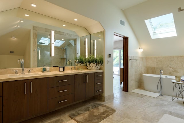 bathroom with plus walk in shower, vaulted ceiling with skylight, vanity, and tile walls