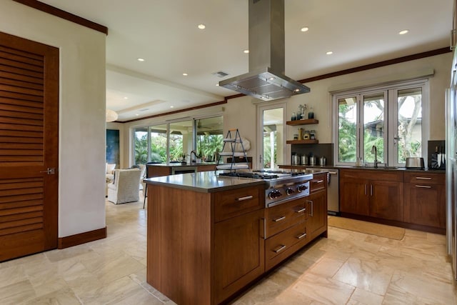 kitchen with island range hood, a kitchen island, sink, and a wealth of natural light