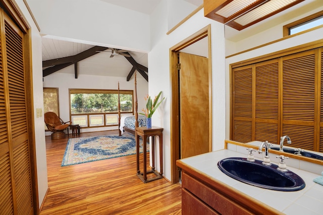 bathroom with oversized vanity, hardwood / wood-style floors, ceiling fan, and vaulted ceiling with beams