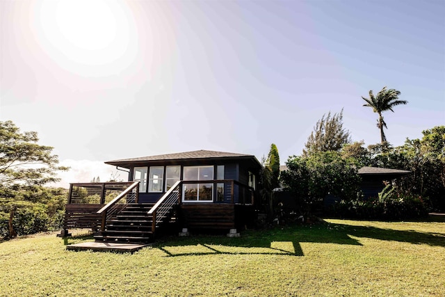 view of front of house with stairway, a sunroom, a shingled roof, a front lawn, and a deck