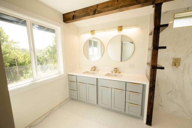 full bathroom featuring beam ceiling, a marble finish shower, double vanity, and a sink