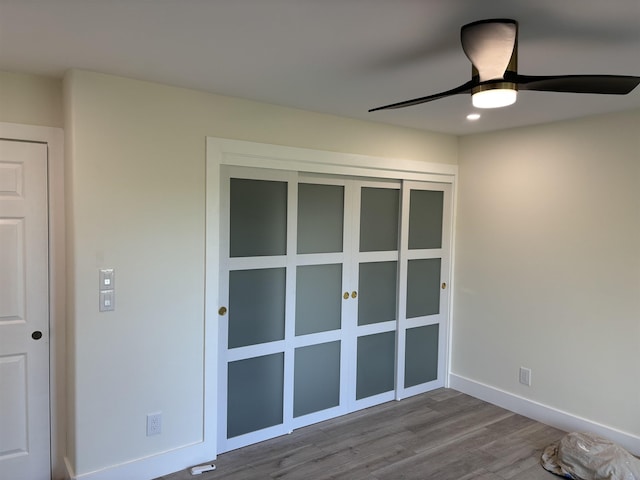 spare room featuring baseboards, wood finished floors, and ceiling fan