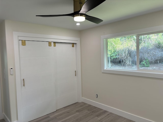 unfurnished bedroom with a closet, a ceiling fan, baseboards, and wood finished floors