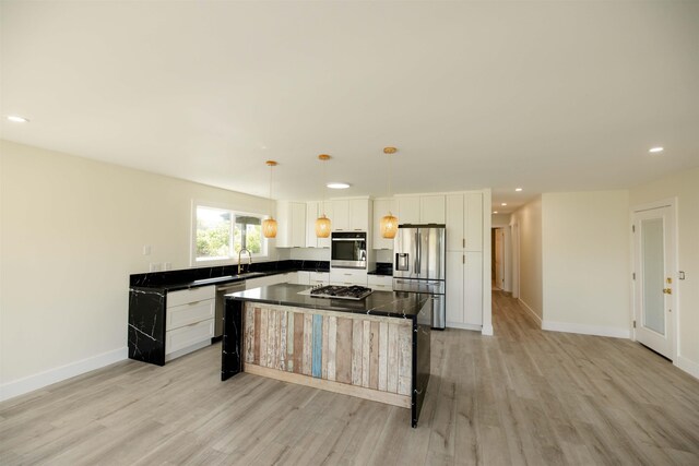 kitchen featuring a sink, stainless steel appliances, white cabinetry, dark countertops, and light wood-type flooring