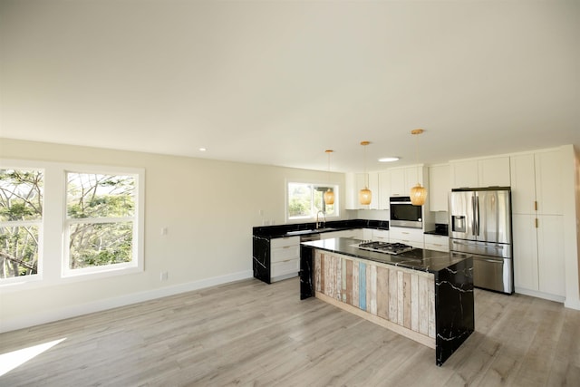 kitchen featuring light wood-type flooring, stainless steel appliances, baseboards, and dark countertops