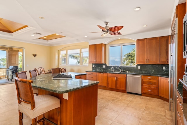 kitchen with a healthy amount of sunlight, stainless steel dishwasher, ceiling fan, a kitchen island, and a breakfast bar area