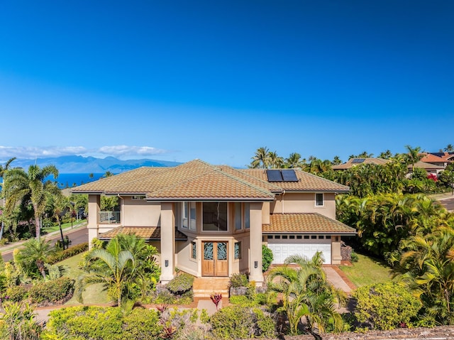 mediterranean / spanish-style home with a mountain view, solar panels, and a garage