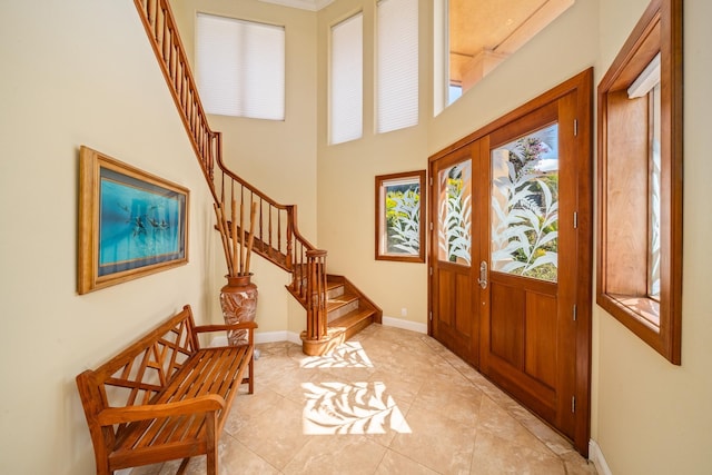 tiled entrance foyer featuring french doors and a towering ceiling