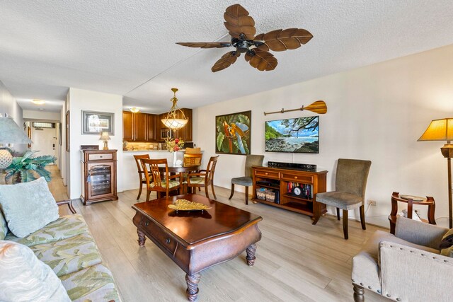 living room featuring ceiling fan, light hardwood / wood-style floors, and a textured ceiling