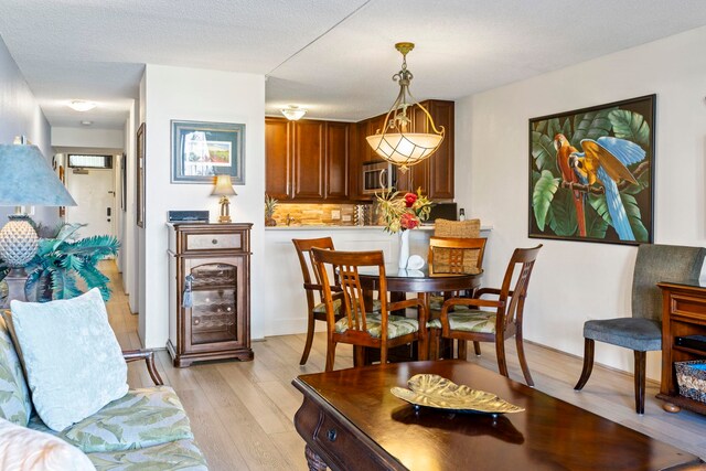 dining room with light hardwood / wood-style floors and a textured ceiling