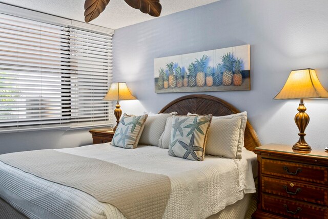 bedroom with ceiling fan and a textured ceiling