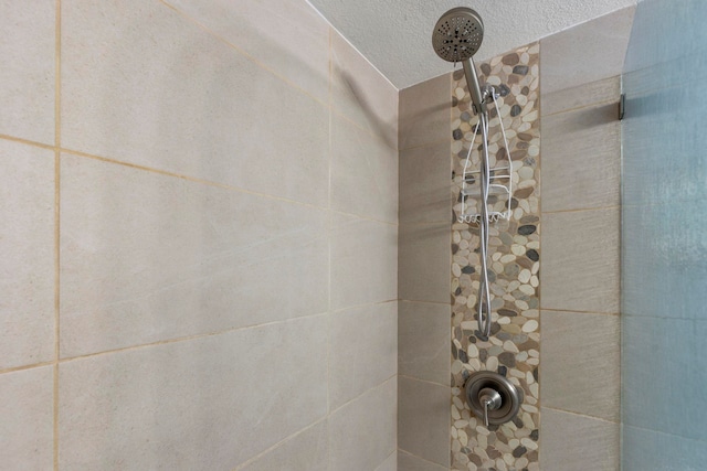 bathroom with a textured ceiling and a tile shower