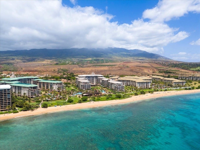 drone / aerial view with a water and mountain view and a view of the beach